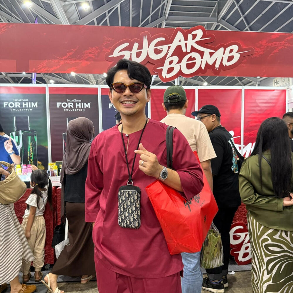 A customer holding a shopping bag at the SugarBomb SG display booth, voted a top affordable perfume store option in Singapore.
