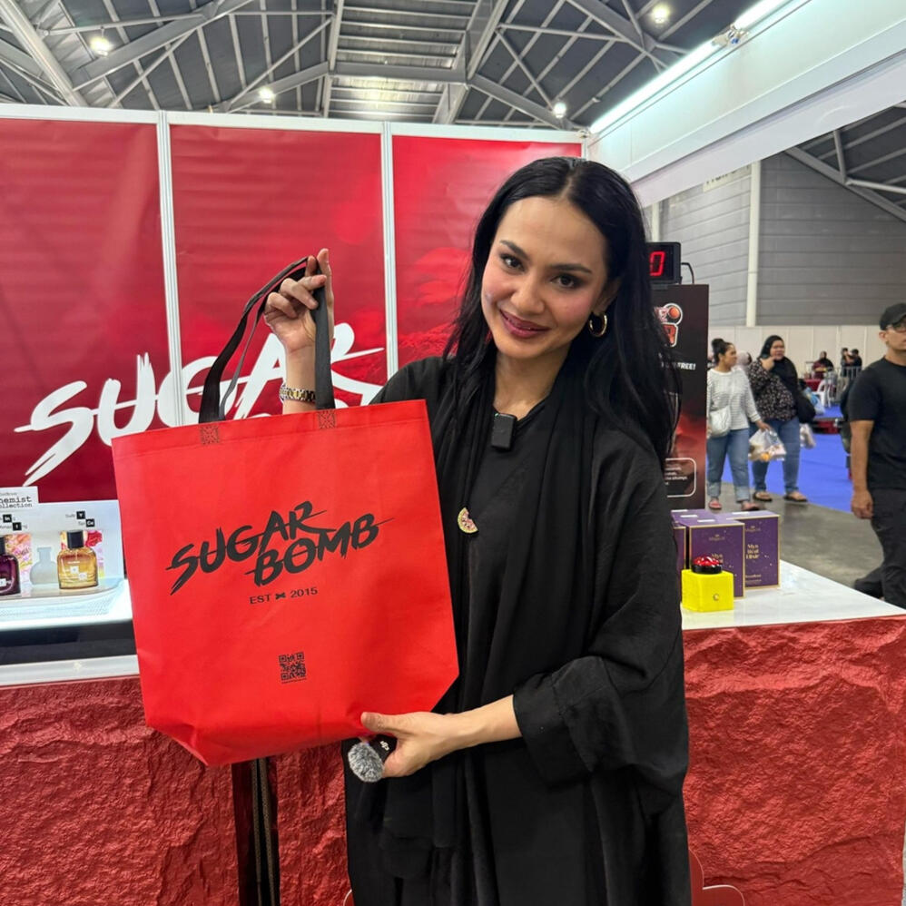 A model presenting a SugarBomb SG shopping bag, featuring the best perfume store deals for long-lasting fragrances in Singapore.