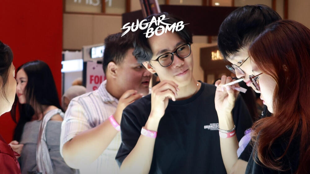 SugarBomb SG Live Fragrance Testing Staff helping a customer try out premium Eau De Parfum options at a SugarBomb perfume store popup event in Singapore.